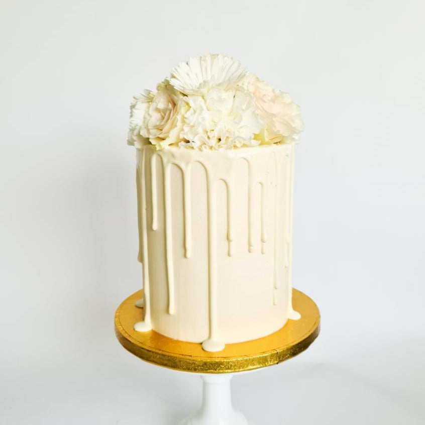 Ivory cream birthday celebration drip cake with fresh flowers on the Isle of Man