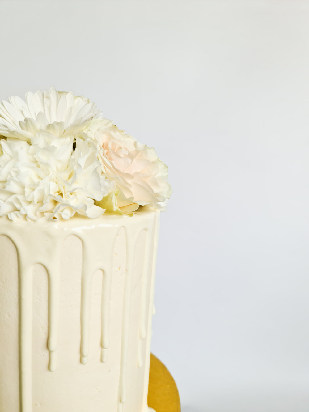 Ivory cream birthday celebration drip cake with fresh flowers on the Isle of Man