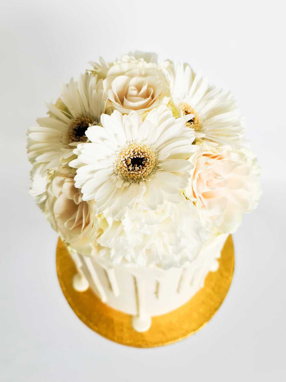 Ivory cream birthday celebration drip cake with fresh flowers on the Isle of Man